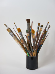 Various dirty paint brushes in a black cup isolated on white background with copy space, close-up....