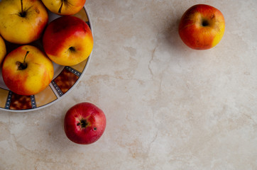 The apples on a plate and two apples on a table.