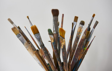 Various dirty paint brushes in a black cup isolated on white background with copy space, close-up. Colorful paintbrushes and artistic Paint Tools 