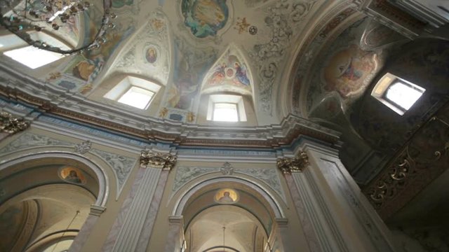 Fragment of the luxurious interior of the Catholic Church. The greatness and beauty of the frescoes on the ceiling and walls. Slow motion