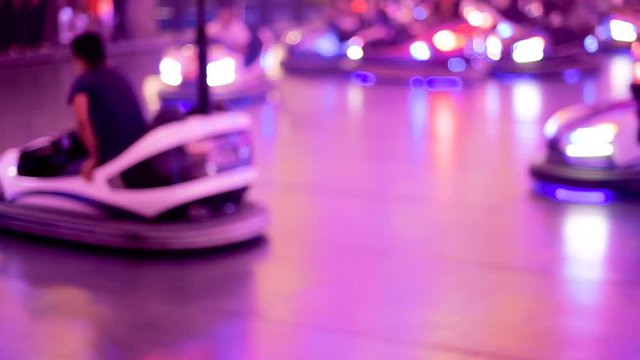 Defocused view of bumper car attraction nighttime view of funny atmosphere at the amusement park 4K UHD cinematic camera used - funny Friday night 