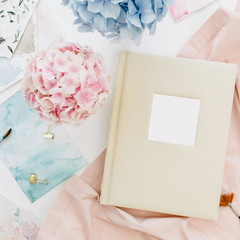 Family wedding photo album, pastel colorful hydrangea flower bouquet, peachy blanket, watercolor paintbrush, decoration on white background. Flat lay, top view.