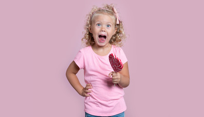 Small happy screaming blond girl with lollipop candyisolated over pink