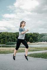 A young and beautiful girl doing outdoor sports. In the park the girl performs sports exercises.