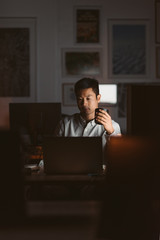 Asian businessman drinking coffee while working in a dark office