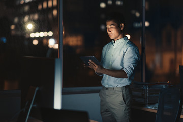 Asian businessman using a digital tablet late at night