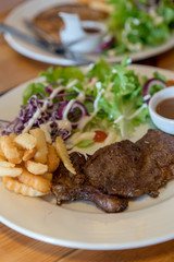Beef steak with vegetable salad and chips on white plate