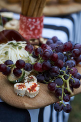 Snacks for beer with different food, close-up. Salty and cheese bar of several kinds of cheese, grapes, olives, nuts, fruits  decorated on table. Holiday party outdoors, picnic