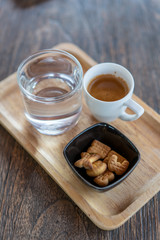 Hot coffee in the cup with the biscuits on wooden table