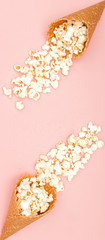 Popcorn in ice cream cones on pink background. Top view