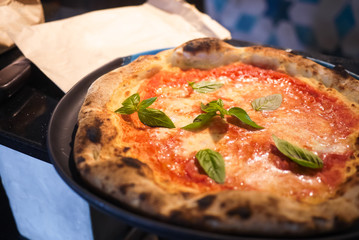 Simple yet perfect. Delicious, cheesy and freshly baked Pizza Margherita, archetype of Neapolitan pizza and Italian unification. Made by professional pizza chef, right from oven. Selective focus.