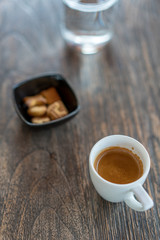 Hot coffee in the cup with the biscuits on wooden table