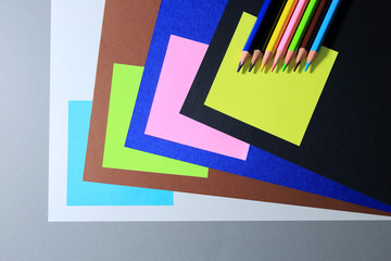 Kartki w różnych kolorach z cieniem i kredki, geometryczny projekt.