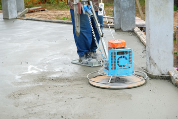 the workers grind the concrete floor at the construction site