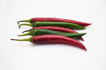 Red and green hot peppers over white background