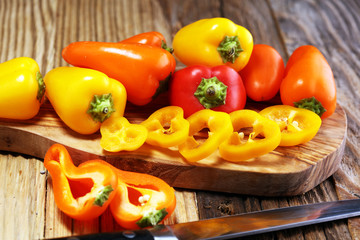 Fresh red, yellow and orange bell pepper on wooden background. raw vegetable.