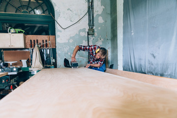 carpenter milling a wooden board in his workshop