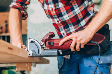 close up of a carpenter hands while milling a wood board  