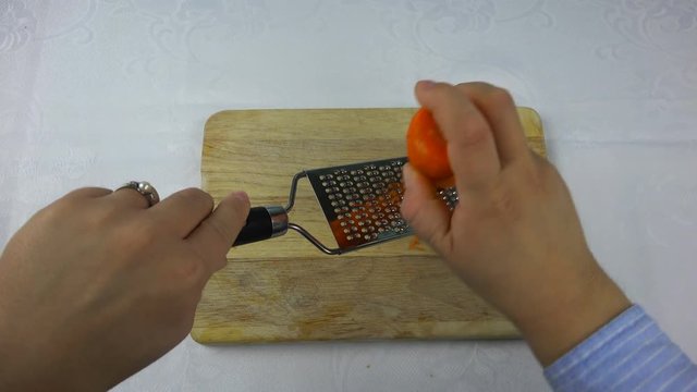 the cook is rubbing carrots on a small grater.