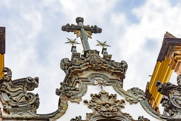 Fototapeta na wymiar Baroque style crucifix on top of ancient and historical church in the city of Sabara in Minas Gerais