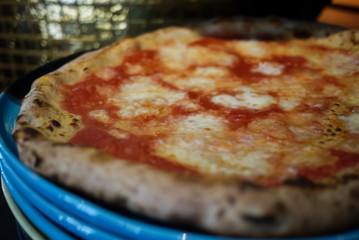 Simple yet perfect. Delicious, cheesy and freshly baked Pizza Margherita, archetype of Neapolitan pizza and Italian unification. Made by professional pizza chef, right from oven. Selective focus.