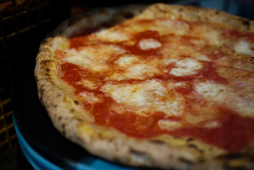 Simple yet perfect. Delicious, cheesy and freshly baked Pizza Margherita, archetype of Neapolitan pizza and Italian unification. Made by professional pizza chef, right from oven. Selective focus.