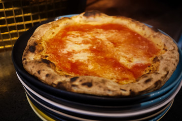 Simple yet perfect. Delicious, cheesy and freshly baked Pizza Margherita, archetype of Neapolitan pizza and Italian unification. Made by professional pizza chef, right from oven. Selective focus.