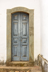 Fototapeta na wymiar Old and aged historic wooden church door in the city of Sabara, Minas Gerais with a stone frame