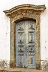 Old and aged historic wooden church door in the city of Sabara, Minas Gerais with a stone frame