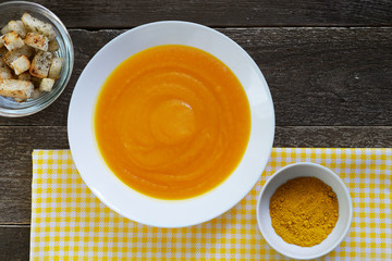 Pumpkin soup in a white plate with croutons and curry seasoning