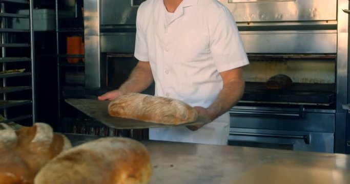 Baker removing freshly baked bread bun from the oven 4k