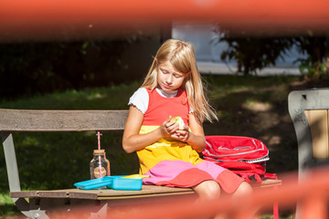 Happy school girl eating apple on school lunch break