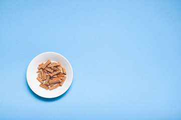 Brown roasted dry bread sticks croutons on white plate with copy space isolated on blue background