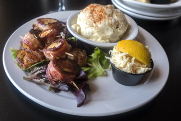 Grilled Bacon Wrapped Scallops Served With Coleslaw and Creamy Potato Salad