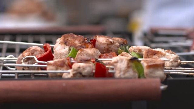 Chicken kebabs with peppers being cooked on a large barbecue grill.