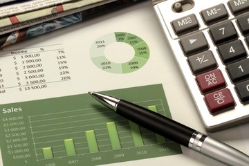 Pen, Calculator And Newspaper On Sales Report Close-up