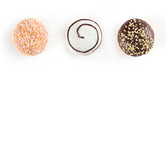 Three sweet doughnuts with chocolate, nuts, white chocolate and coconuts isolated on white background. Top view and copy space