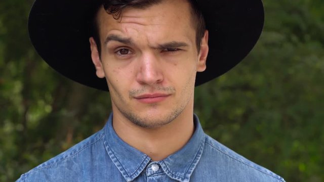 Young hipster man in hat laughing, relaxed in front of the camera