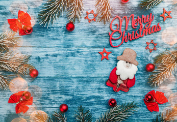 Wooden azure background with red christmas elements. Fir branches and light effect.