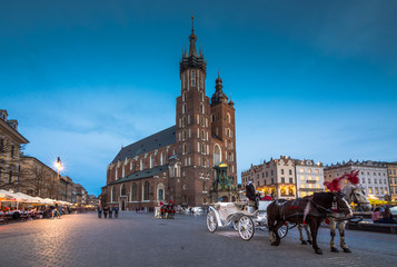 Naklejka na ściany i meble Old town market square of Krakow, Poland with horse carriages.