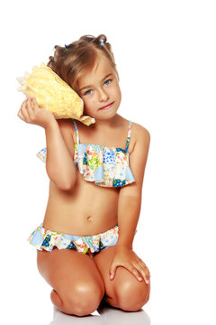 Little girl in a swimsuit with a seashell