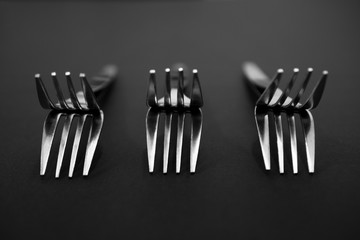 Unique arrangement of silver forks on black background.