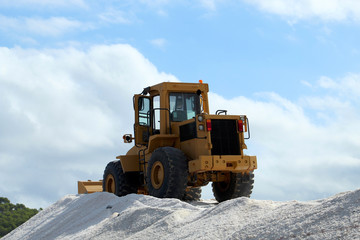 Bulldozer on salt mountain in industrial salt marsh