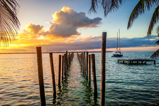 Glowing pink and orange sunset over the unfinished pier on the tiny Caribbean Island of Tobacco Caye in Belize's barrier reef