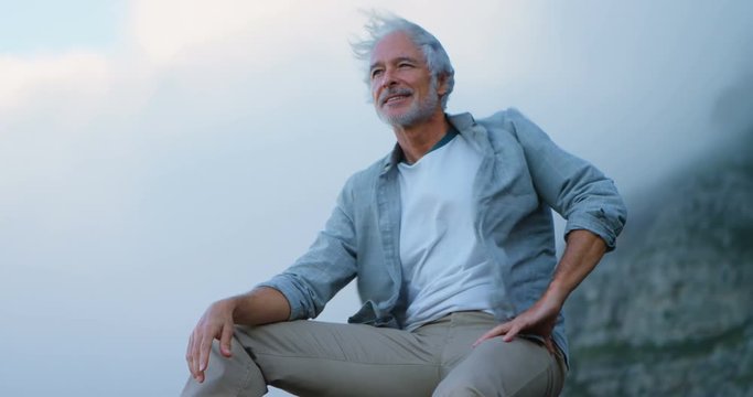 Senior man relaxing on a rock at countryside 4k