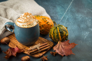 Pumpkin latte with spices and whipped cream on top on a wooden background. Copy space. Autumn or winter hot drink.
