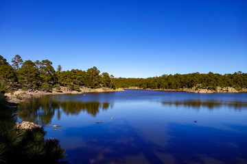 Deep crystal blue waters of Lake Arareco, surrounded by coniferous pine forest and strange rock formations near Creel in Chihuahua state of northern Mexico