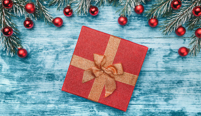 New Year greeting card on azure background, a red gift. Fir trees with red balls. Top view