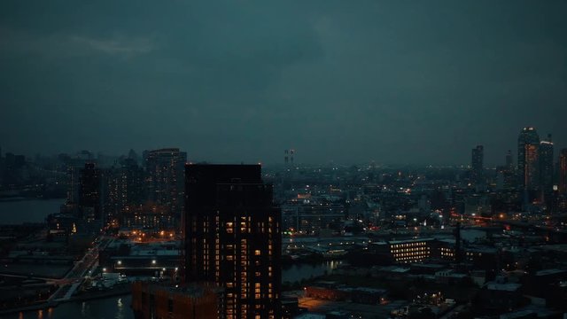 Drone approaching Long Island City Queens from Brooklyn.  Gritty city view at hazy sunset in 4K
