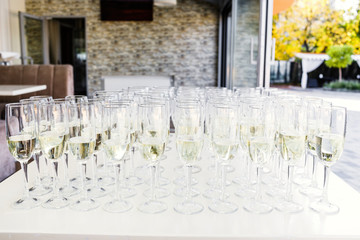 Full cold champagne flutes stand between buckets on dinner table